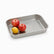 Perforated stainless steel drainer tray with 2 red apples and a lemon, half left empty