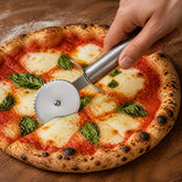 Hand slicing a margherita pizza with a stainless steel pizza cutter