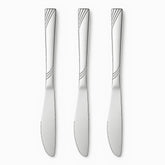 Three stainless steel table knives with engraved wave handles and serrated edges lined up in a row