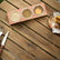 Top view of wooden stand with 3 steel cups of sesame, spices and sauce next to a food plate