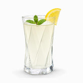 Twisted diamond-cut glass tumbler with hexagonal base filled with lemonade, mint and a lemon wedge