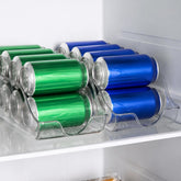 Two clear can organizers holding green and blue drink cans on a fridge shelf