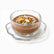 Clear hammered glass dessert bowl on wavy saucer with meghli, coconut, walnuts and pistachios