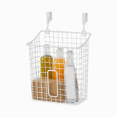 White wire over-the-door basket with hooks holding oil, juice and water bottles and a kraft box