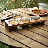 Wooden stand with 3 steel cups of sesame, spices and sauce on a garden table